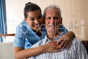 Smiling female doctor standing by senior man sitting in nursing home