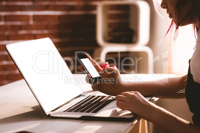 Attentive executive using laptop and mobile phone