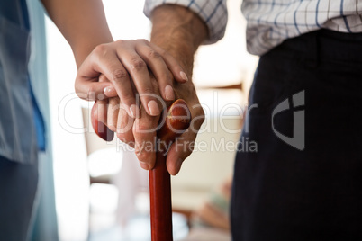 Cropped hands of female doctor and senior man holding walking cane