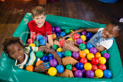 High angle portrait of children sitting on ball pool