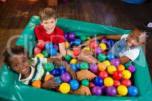 High angle portrait of children sitting on ball pool