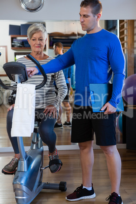 Physiotherapist showing workout record on exercise bike