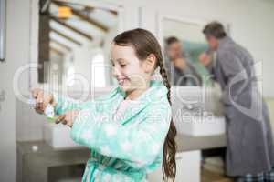 Smiling girl putting toothpaste on toothbrush