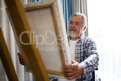 Senior man looking at painting while sitting on wheelchair