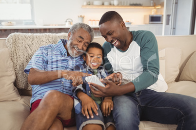 Smiling multi-generation family using mobile phone in living room