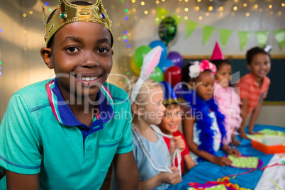 Portrait of boy wearing crown with friends in background