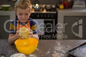 Boy kneading dough over yellow bowl