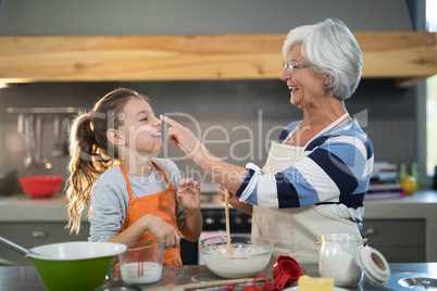Grandmother putting flour on granddaughters nose