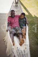 Smiling father and son relaxing on a hammock