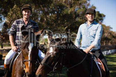 Two male friends riding horse in the ranch