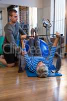 Physiotherapist assisting senior woman in performing exercise with resistance band