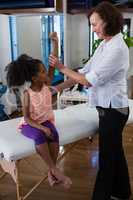 Physiotherapist giving hand massage to a girl