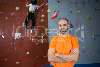 Trainer standing with arms crossed in fitness studio