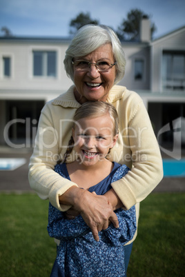 Smiling grandmother and granddaughter embracing each other in garden