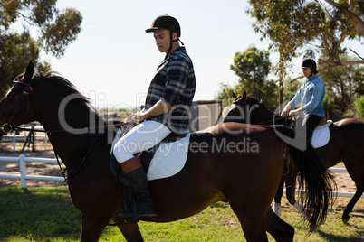 Two male friends riding horse in the ranch