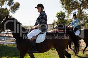 Two male friends riding horse in the ranch