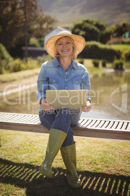 Smiling senior woman using laptop in park