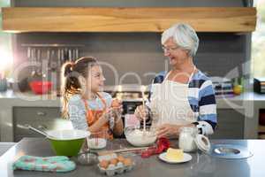 Granddaughter mixing flour in a bowl with her granddaughter