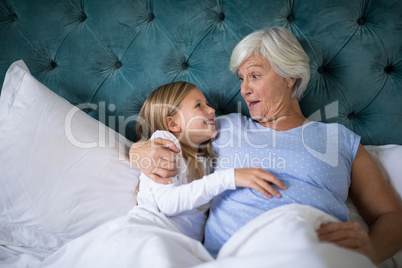 Grandmother and granddaughter interacting with each other on bed