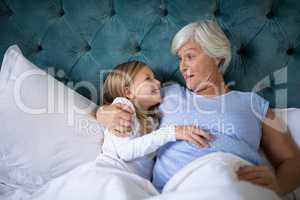 Grandmother and granddaughter interacting with each other on bed
