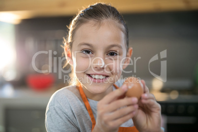 Smiling girl holding eggs with flour on her nose