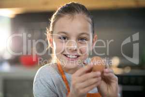 Smiling girl holding eggs with flour on her nose