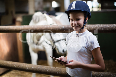 Teenage girl using digital tablet in the stable