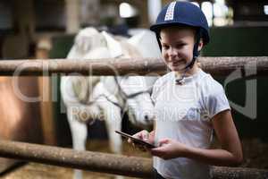 Teenage girl using digital tablet in the stable