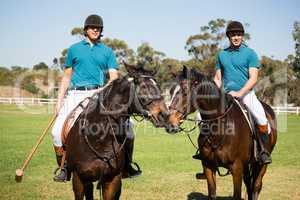 Two male jockeys riding horse in the ranch