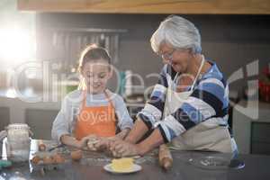 Grandmother and granddaughter kneading dough