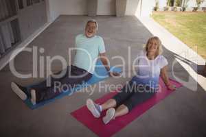 Smiling senior couple relaxing on exercise mat