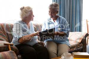 Senior woman discussing with doctor while reading book sofa