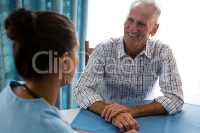 Man interacting with female doctor at table in retirement home