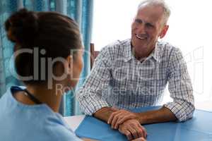 Man interacting with female doctor at table in retirement home