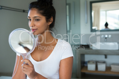 Woman applying lipstick in bathroom