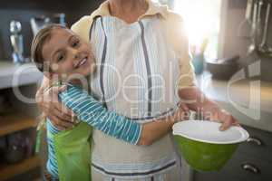 Grandmother and granddaughter embracing in the kitchen