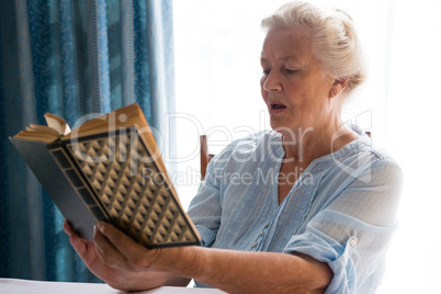 Senior woman reading book while sitting at table