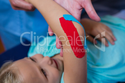 Physiotherapist sticking tape on girl patient