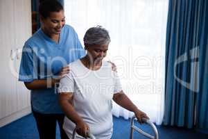 Nurse hepling senior woman in walking with walker
