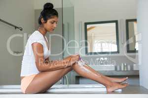 Full length of woman shaving leg in bathroom