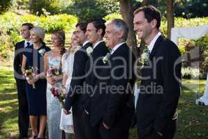 Happy bride and groom standing with guests