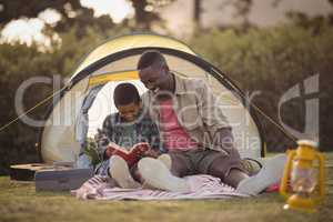 Father and son reading book in park