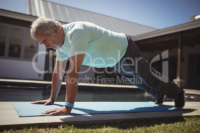 Senior man doing push-up near swimming pool