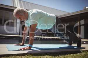 Senior man doing push-up near swimming pool