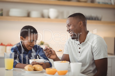 Father and son having breakfast in kitchen