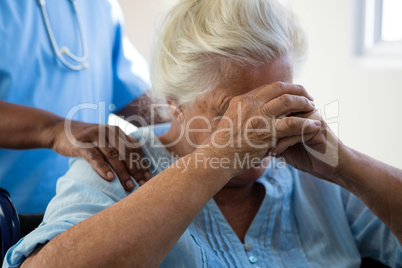 Nurse consoling senior woman at nursing home