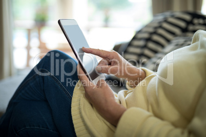 Senior woman using digital tablet on sofa