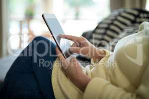 Senior woman using digital tablet on sofa