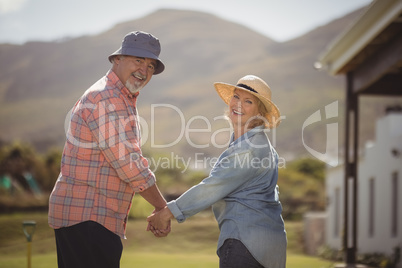 Senior couple holding hands and standing in lawn on a sunny day