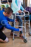 Physiotherapist helping patient to walk with walking frame
